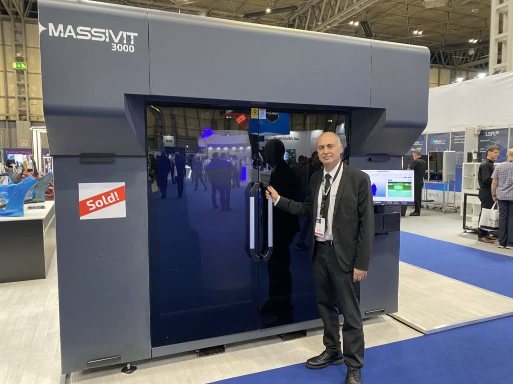Massivit VP of Sales and Marketing, Avi Cohen, standing in front of the Massivit 3000 3D printers