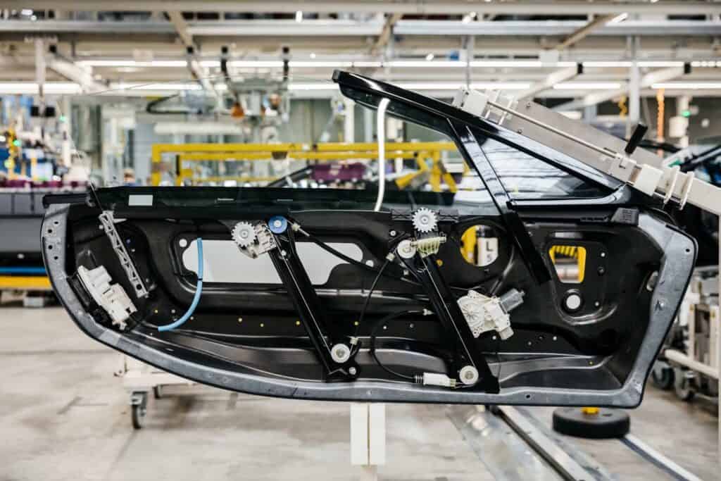 An exposed BMW i8 Roadster door panel on the production line, featuring 3D printed car parts integrated into the window regulator assembly