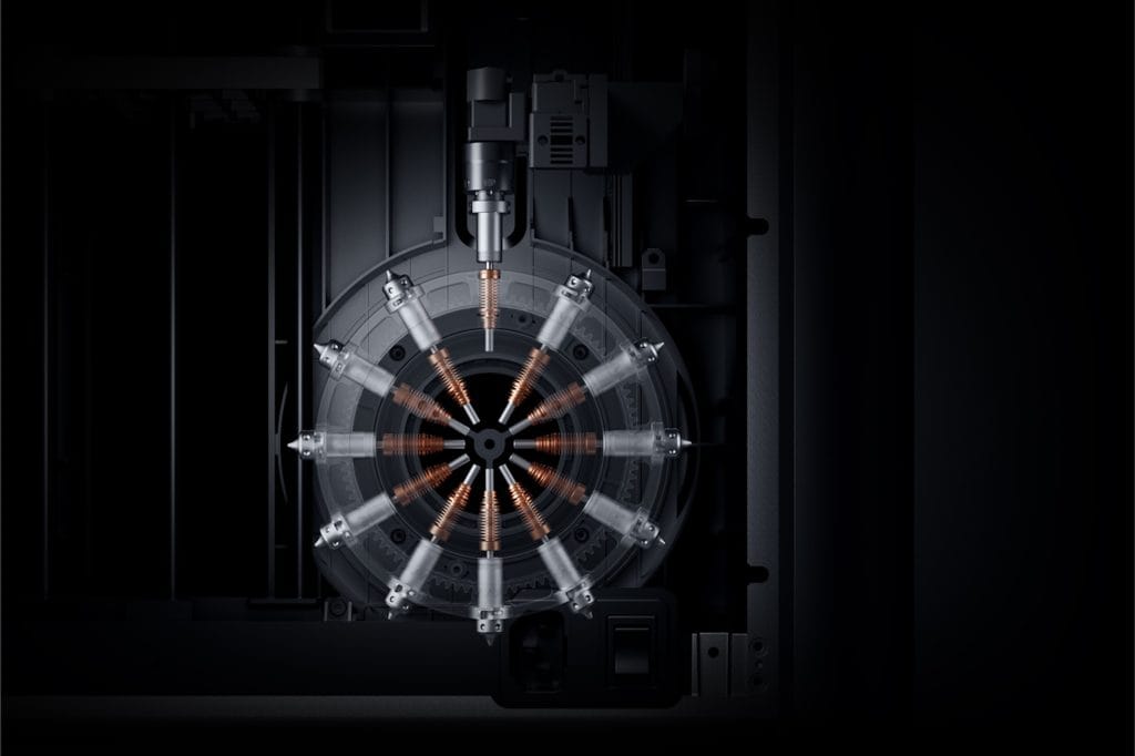 Close-up view of the 12-nozzle OmniElement Automatic Nozzle Switching System inside the MOVA AtomForm Palette 300, showing nozzles arranged in a radial configuration with copper heating elements