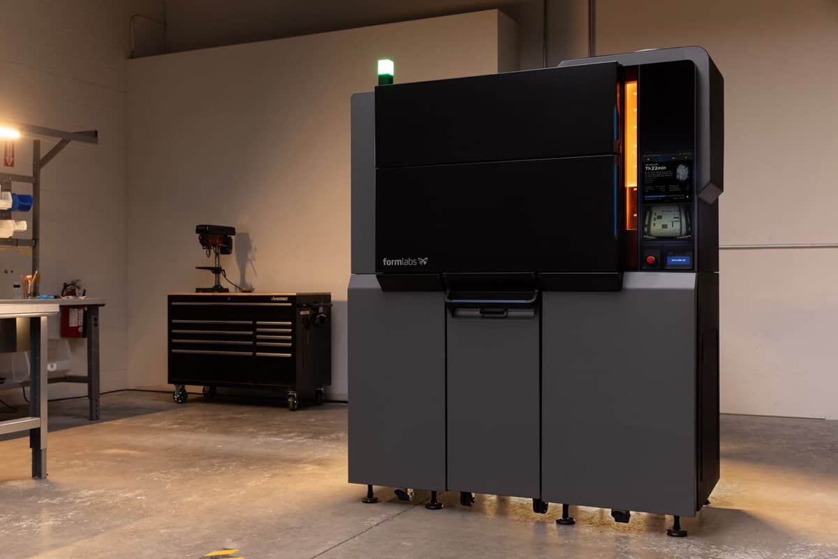 The Formlabs Fuse X1 large-format SLS 3D printer installed in an industrial workshop, green status light lit, with the touchscreen showing a 7h 22min Nylon 12 print job